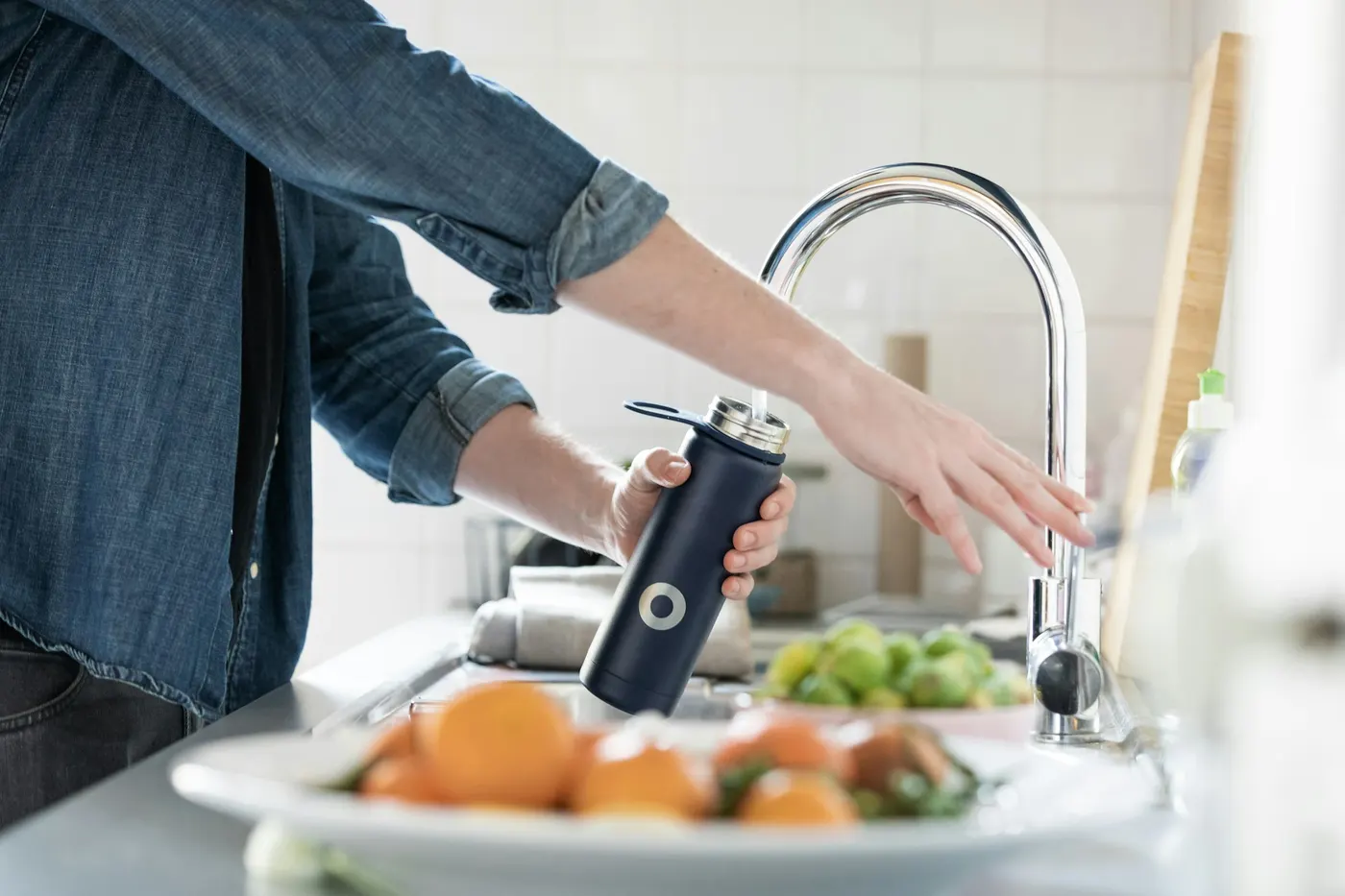 Filling a water bottle at a kitchen sink