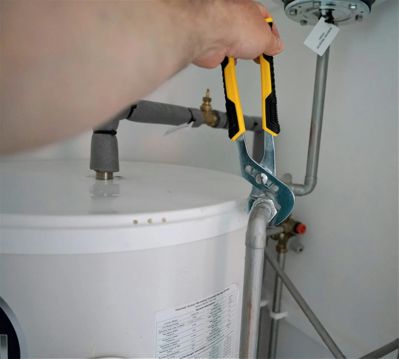 A plumber tightening a fitting on a tank with a wrench